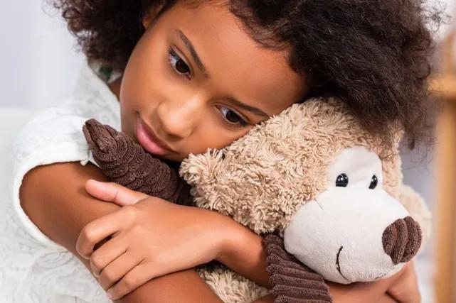 a sad child holding a stuffed animal