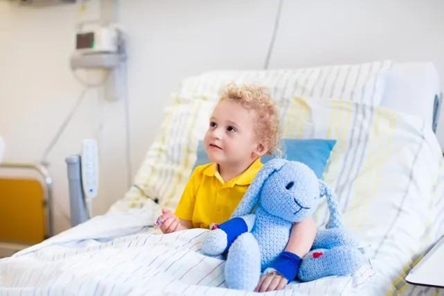 a child in a hospital bed with a stuffed animal