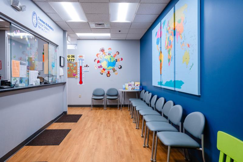 a colorful hallways with a front desk and empty chairs