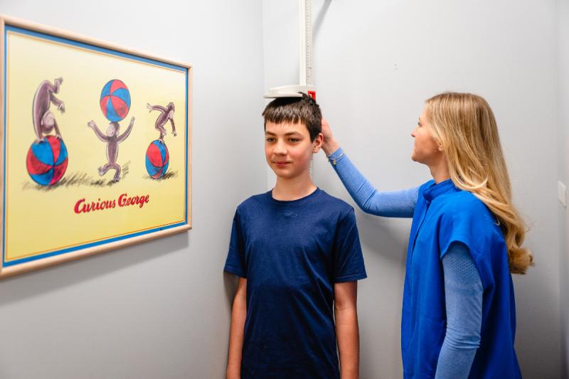 a teenage boy getting his height measured by a woman provider